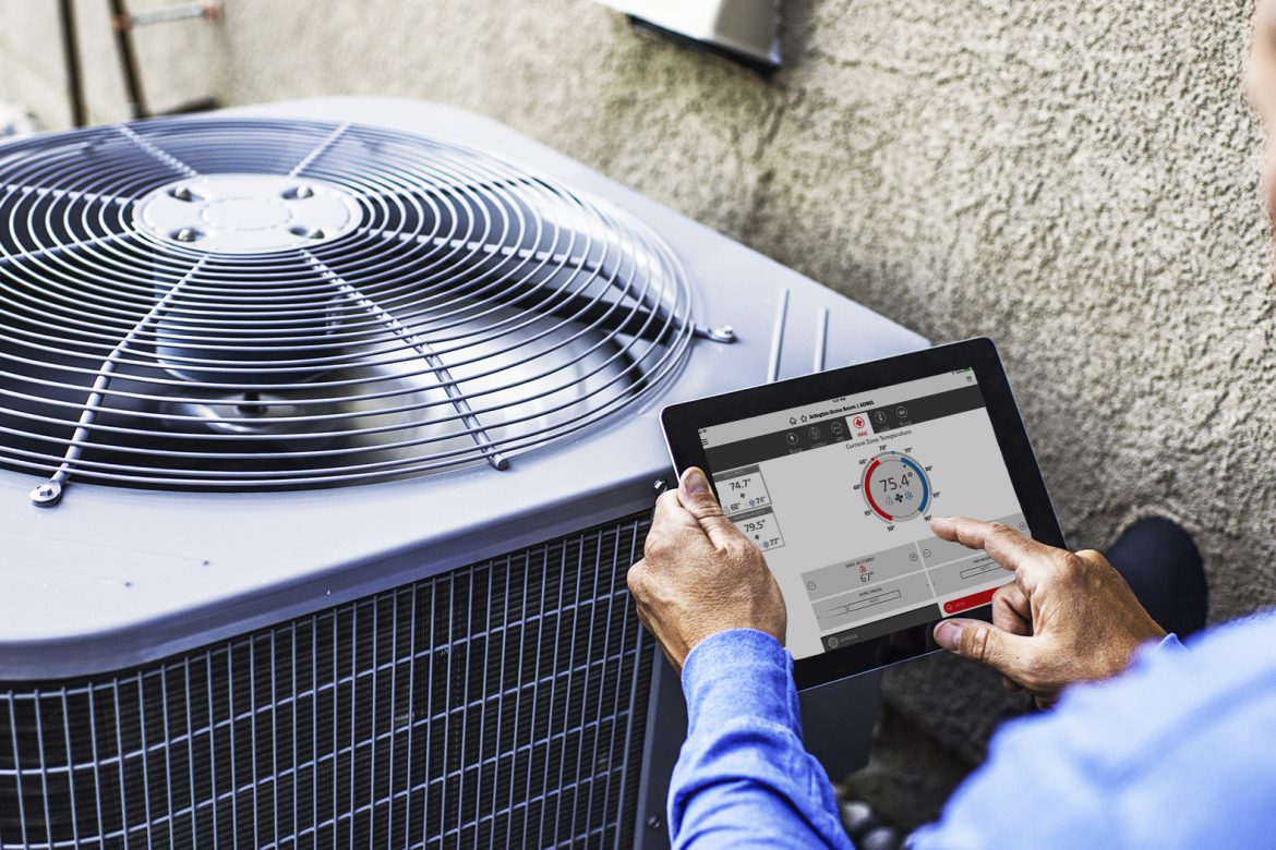 Person using energy control systems on tablet in front of a commercial HVAC unit