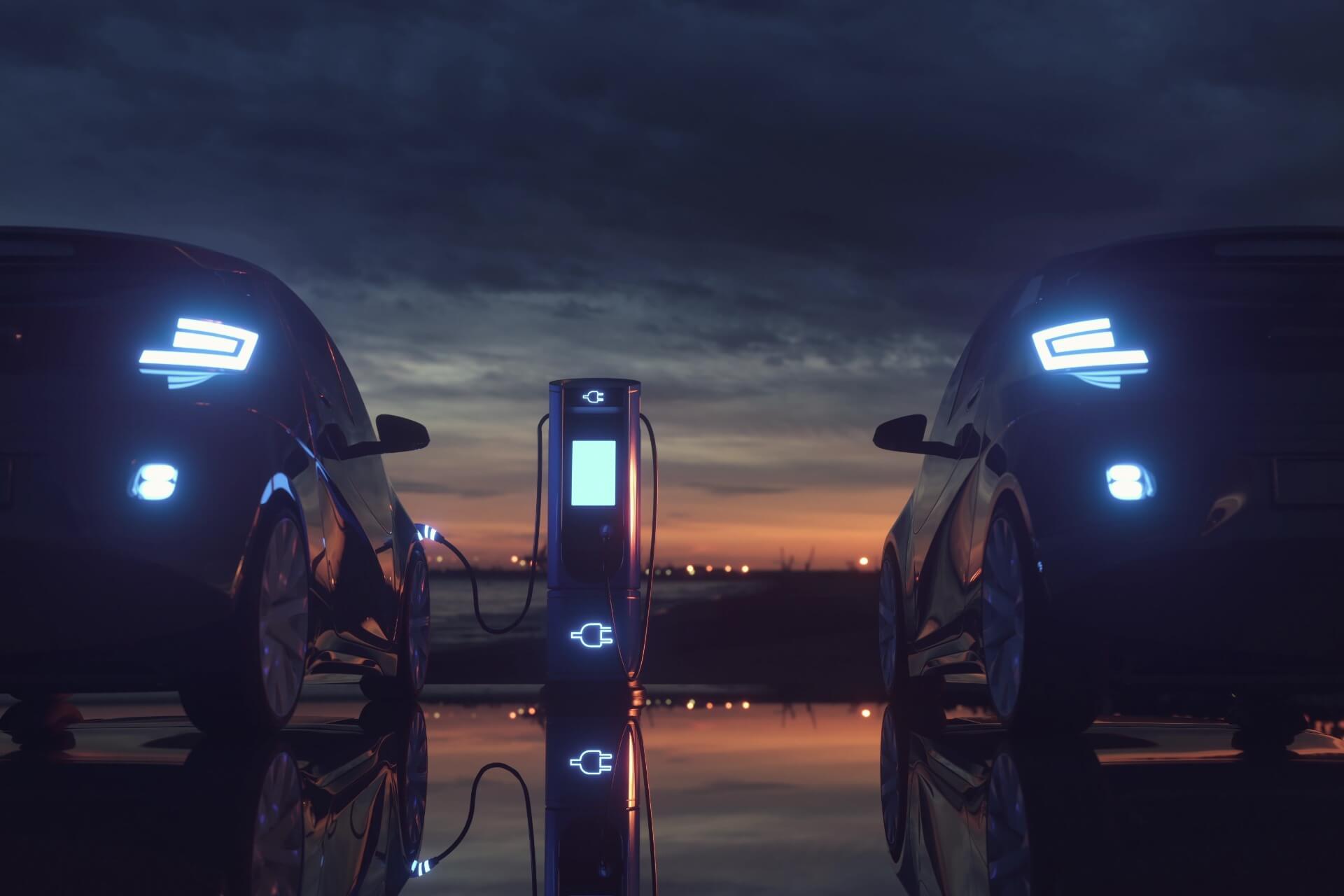 Two electric vehicles charging at an electric car station at sunset