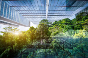 Glass building viewed from ground up surrounded by bright green treens